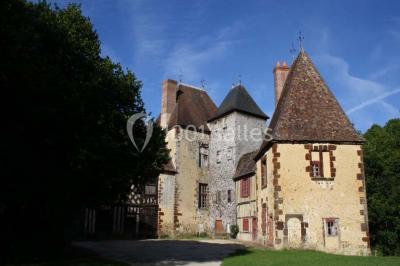 Salle de bain avec lavabo moderne, douche vitrée et miroir, dans une pièce aux poutres apparentes en bois.