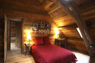 Salle de bain avec lavabo moderne, douche vitrée et miroir, dans une pièce aux poutres apparentes en bois.