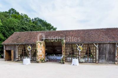 Salle de bain avec lavabo moderne, douche vitrée et miroir, dans une pièce aux poutres apparentes en bois.