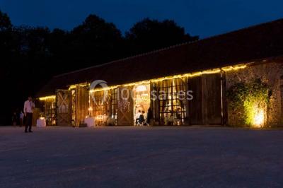 Salle de bain avec lavabo moderne, douche vitrée et miroir, dans une pièce aux poutres apparentes en bois.