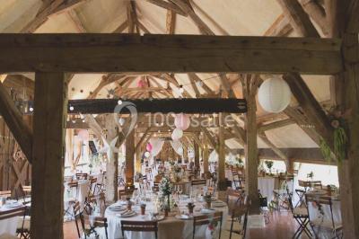 Salle de bain avec lavabo moderne, douche vitrée et miroir, dans une pièce aux poutres apparentes en bois.