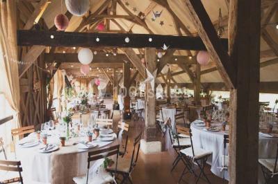 Salle de bain avec lavabo moderne, douche vitrée et miroir, dans une pièce aux poutres apparentes en bois.