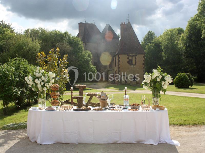 Table dressée en extérieur avec des fleurs blanches, des plats variés et un château en arrière-plan.