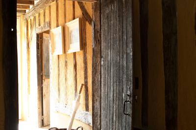 Salle de bain avec lavabo moderne, douche vitrée et miroir, dans une pièce aux poutres apparentes en bois.