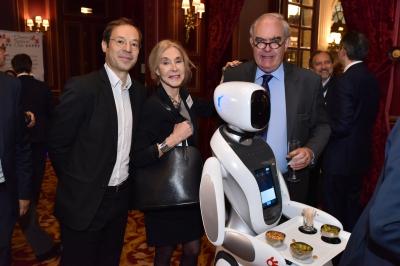 Robot humanoïde blanc équipé d'un écran et d'un plateau, présenté dans un environnement intérieur avec plantes et…