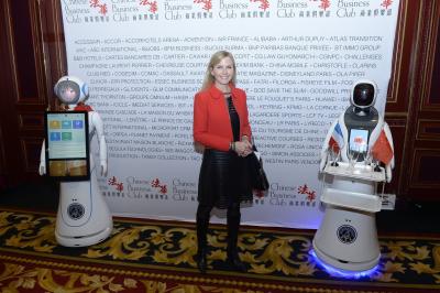 Robot humanoïde blanc équipé d'un écran et d'un plateau, présenté dans un environnement intérieur avec plantes et…