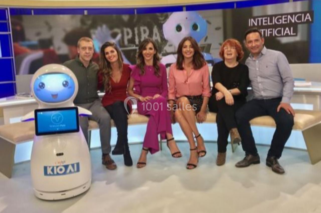 Un groupe de personnes assises sur un canapé avec un robot humanoïde dans un studio télévisé sur l'intelligence artificielle.