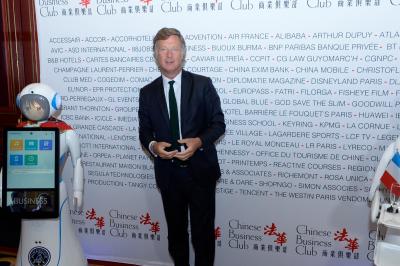 Robot humanoïde blanc équipé d'un écran et d'un plateau, présenté dans un environnement intérieur avec plantes et…