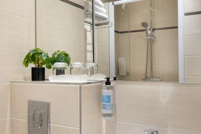 Salle de bain moderne avec douche, lavabo, miroir, toilettes et étagère murale garnie de serviettes pliées.