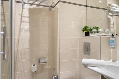Salle de bain moderne avec douche, lavabo, miroir, toilettes et étagère murale garnie de serviettes pliées.