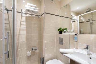 Salle de bain moderne avec douche, lavabo, miroir, toilettes et étagère murale garnie de serviettes pliées.