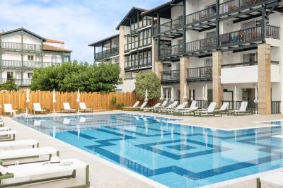 Lavabo blanc avec miroir en bois et douche à carreaux verts dans une salle de bain moderne.