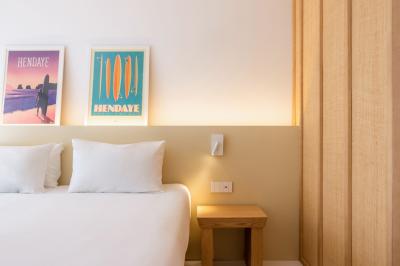 Lavabo blanc avec miroir en bois et douche à carreaux verts dans une salle de bain moderne.