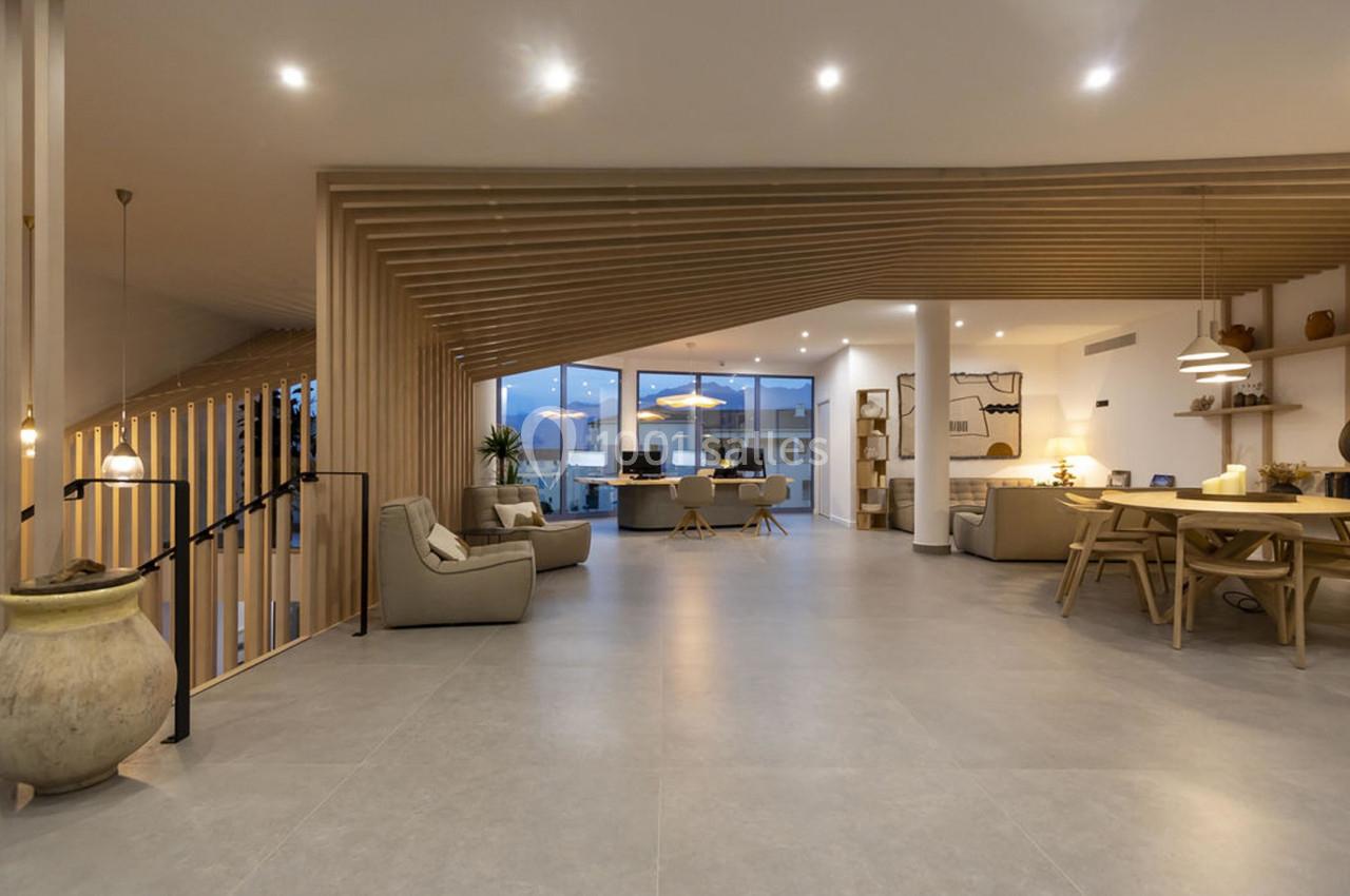 Espace intérieur moderne avec un salon ouvert, des meubles en bois clair et un éclairage chaleureux.