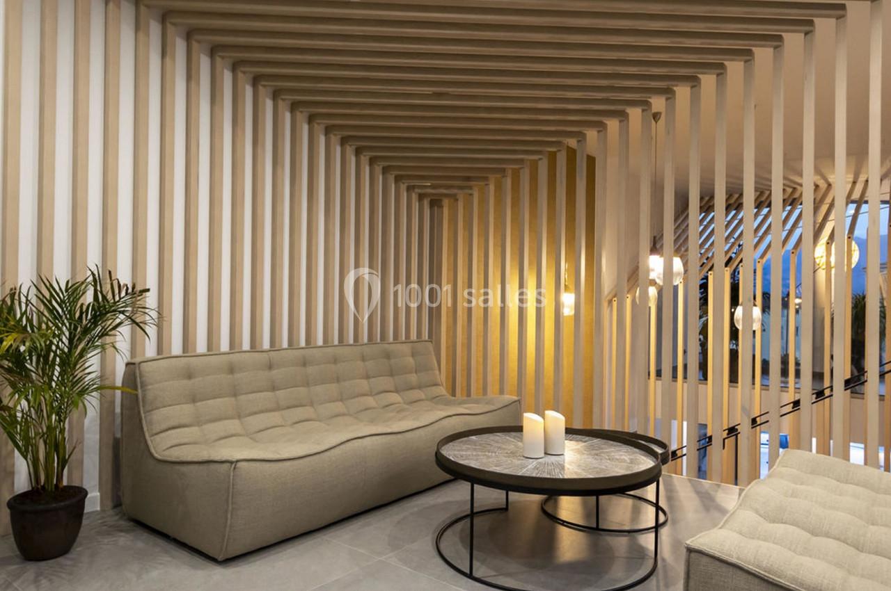 Salon moderne avec canapé beige, table basse ronde en marbre, bougies et décor en bois avec éclairage doux.