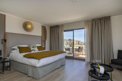 Chambre lumineuse avec lit double, décoration moderne, grande baie vitrée donnant sur une terrasse avec vue extérieure.