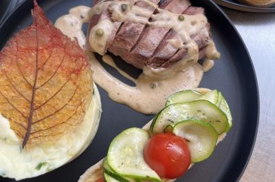 Assiette de légumes rôtis avec pommes de terre violettes, garnie de pousses fraîches et de fleurs comestibles.