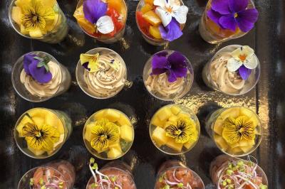 Assiette de légumes rôtis avec pommes de terre violettes, garnie de pousses fraîches et de fleurs comestibles.