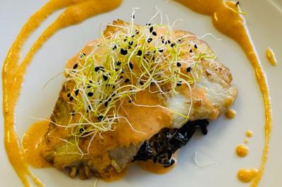 Assiette de légumes rôtis avec pommes de terre violettes, garnie de pousses fraîches et de fleurs comestibles.