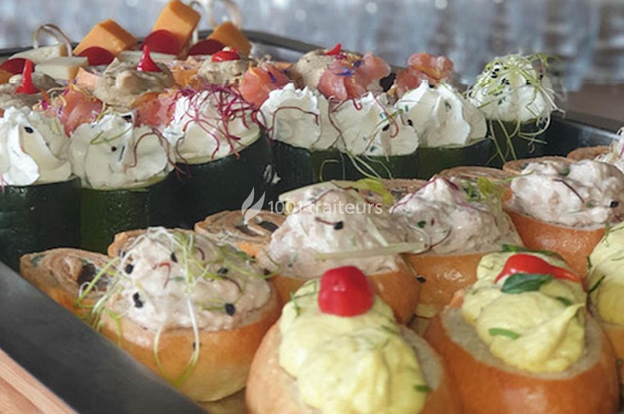 Plateau de bouchées apéritives variées avec légumes, fromage frais, saumon, herbes et garnitures colorées.