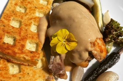 Assiette de légumes rôtis avec pommes de terre violettes, garnie de pousses fraîches et de fleurs comestibles.