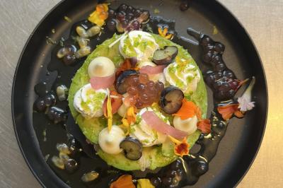 Assiette de légumes rôtis avec pommes de terre violettes, garnie de pousses fraîches et de fleurs comestibles.