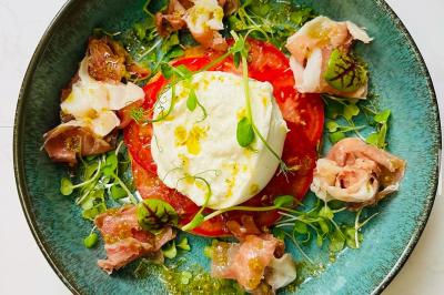 Assiette de légumes rôtis avec pommes de terre violettes, garnie de pousses fraîches et de fleurs comestibles.