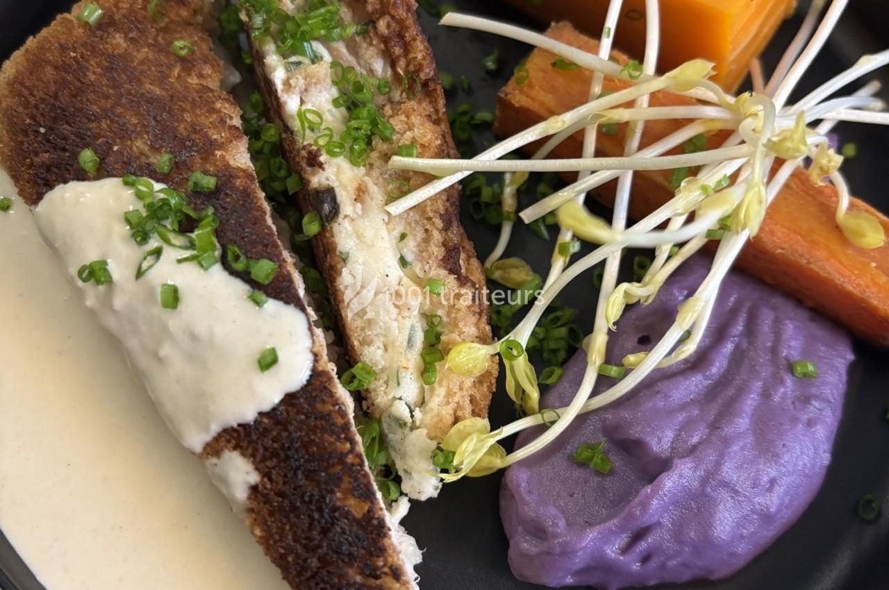 Assiette composée d'un croque revisité, purée violette, légumes racines et germes, nappée de sauce blanche.