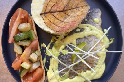 Assiette de légumes rôtis avec pommes de terre violettes, garnie de pousses fraîches et de fleurs comestibles.