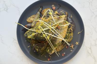 Assiette de légumes rôtis avec pommes de terre violettes, garnie de pousses fraîches et de fleurs comestibles.