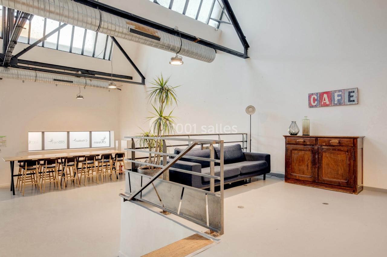 Espace intérieur lumineux avec un canapé, une table longue, des chaises, une armoire en bois et une décoration ’CAFE’.