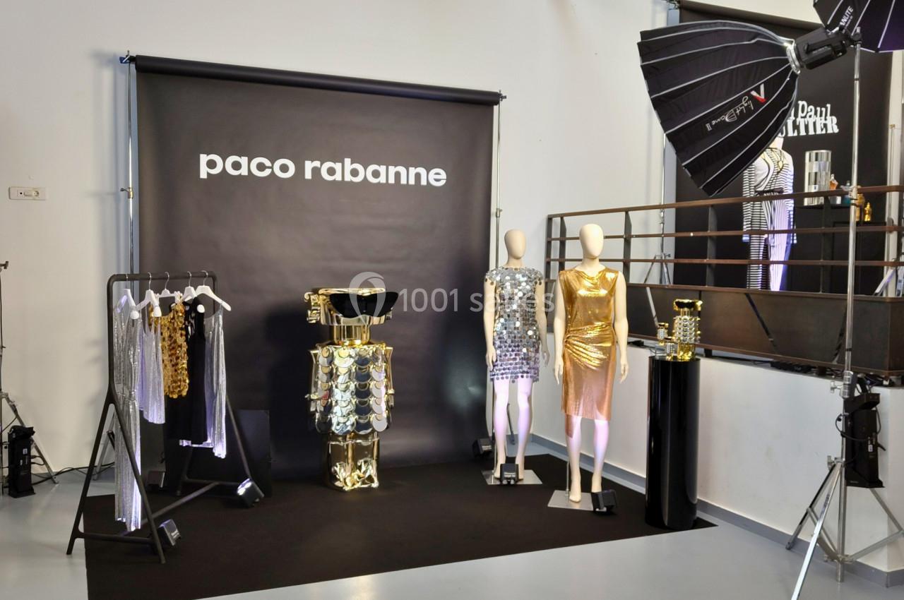 Mannequins et vêtements métallisés exposés devant un fond noir avec le logo Paco Rabanne, éclairage de studio.