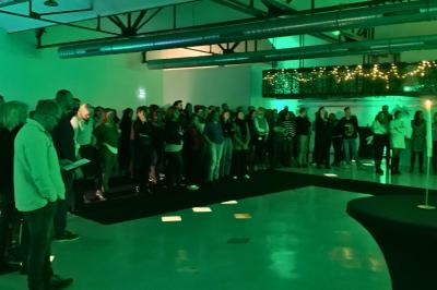 Intérieur d'un grand espace industriel lumineux avec sol clair, murs blancs, poutres métalliques et conduits apparents.