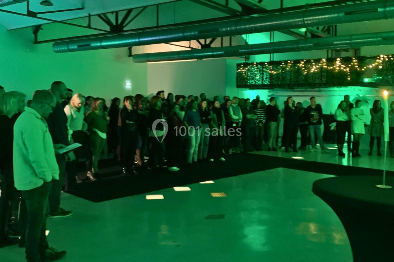 Un groupe de personnes rassemblées dans une salle éclairée par des lumières vertes, avec un décor industriel.
