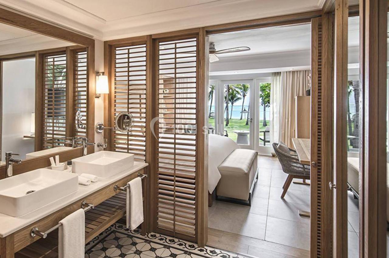 Salle de bain moderne avec double vasque, miroir, cloison en bois ajouré et vue sur une chambre lumineuse donnant sur l…