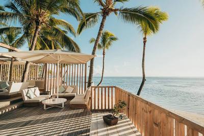 Miniature Location salle Flic-en-Flacq (District de Rivière Noire) - Hôtel Sugar Beach #13 Chambre lumineuse avec lit double, bureau, fauteuil, étagères en bois et vue sur une salle de bain ouverte.