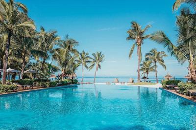 Miniature Location salle Flic-en-Flacq (District de Rivière Noire) - Hôtel Sugar Beach #4 Chambre lumineuse avec lit double, bureau, fauteuil, étagères en bois et vue sur une salle de bain ouverte.