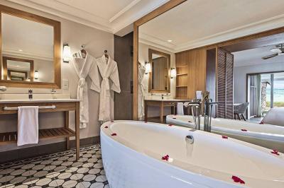 Miniature Location salle Flic-en-Flacq (District de Rivière Noire) - Hôtel Sugar Beach #17 Chambre lumineuse avec lit double, bureau, fauteuil, étagères en bois et vue sur une salle de bain ouverte.