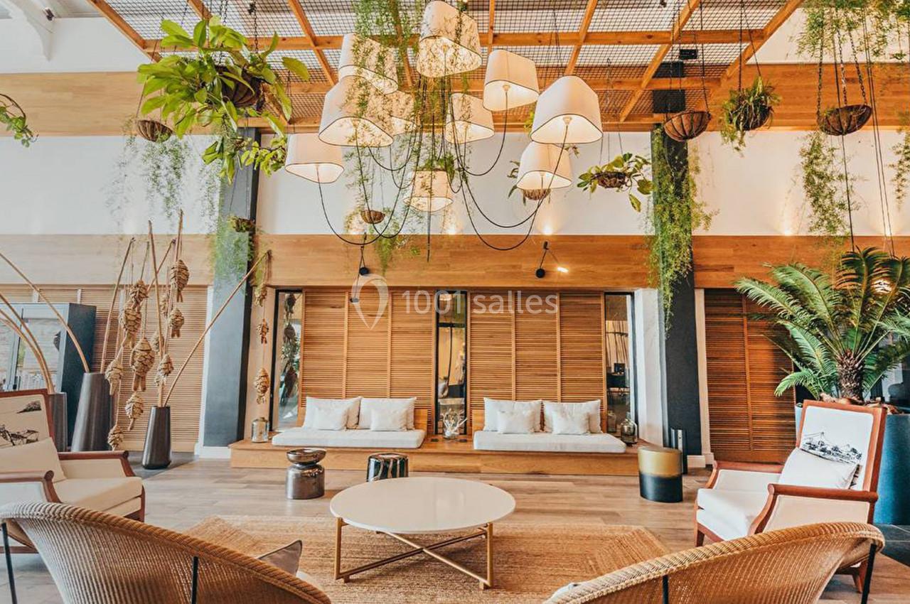 Espace lounge lumineux avec mobilier en rotin, plantes suspendues et décoration naturelle dans un cadre chaleureux.