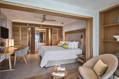 Miniature Location salle Flic-en-Flacq (District de Rivière Noire) - Hôtel Sugar Beach #22 Chambre lumineuse avec lit double, bureau, fauteuil, étagères en bois et vue sur une salle de bain ouverte.