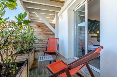 Vue d'une cour intérieure avec balcons en bois rouge, grandes baies vitrées et éclairage chaleureux au crépuscule.