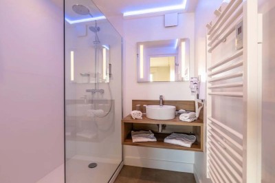 Vue d'une cour intérieure avec balcons en bois rouge, grandes baies vitrées et éclairage chaleureux au crépuscule.