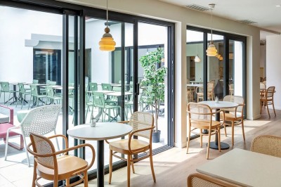 Vue d'une cour intérieure avec balcons en bois rouge, grandes baies vitrées et éclairage chaleureux au crépuscule.
