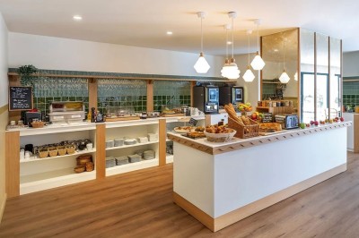 Vue d'une cour intérieure avec balcons en bois rouge, grandes baies vitrées et éclairage chaleureux au crépuscule.