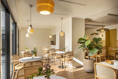 Vue d'une cour intérieure avec balcons en bois rouge, grandes baies vitrées et éclairage chaleureux au crépuscule.
