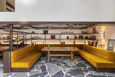 Vue d'une cour intérieure avec balcons en bois rouge, grandes baies vitrées et éclairage chaleureux au crépuscule.