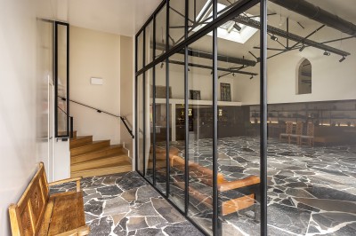 Vue d'une cour intérieure avec balcons en bois rouge, grandes baies vitrées et éclairage chaleureux au crépuscule.