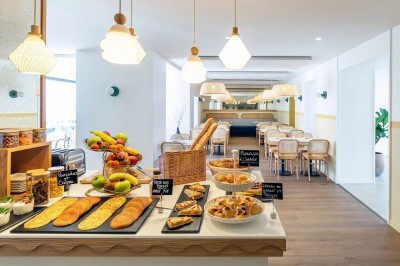 Lavabo moderne avec un distributeur de savon blanc et une serviette pliée dans une salle de bain lumineuse.