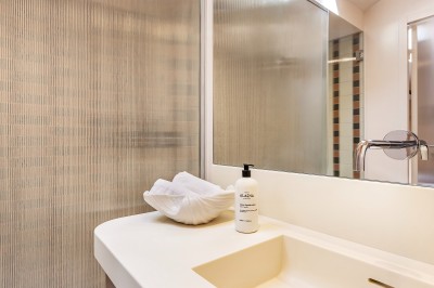 Lavabo moderne avec un distributeur de savon blanc et une serviette pliée dans une salle de bain lumineuse.