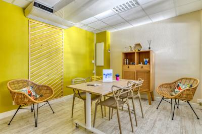 Chambre lumineuse avec lit double, tableau mural, télévision, balcon et mobilier simple sur un sol en parquet.